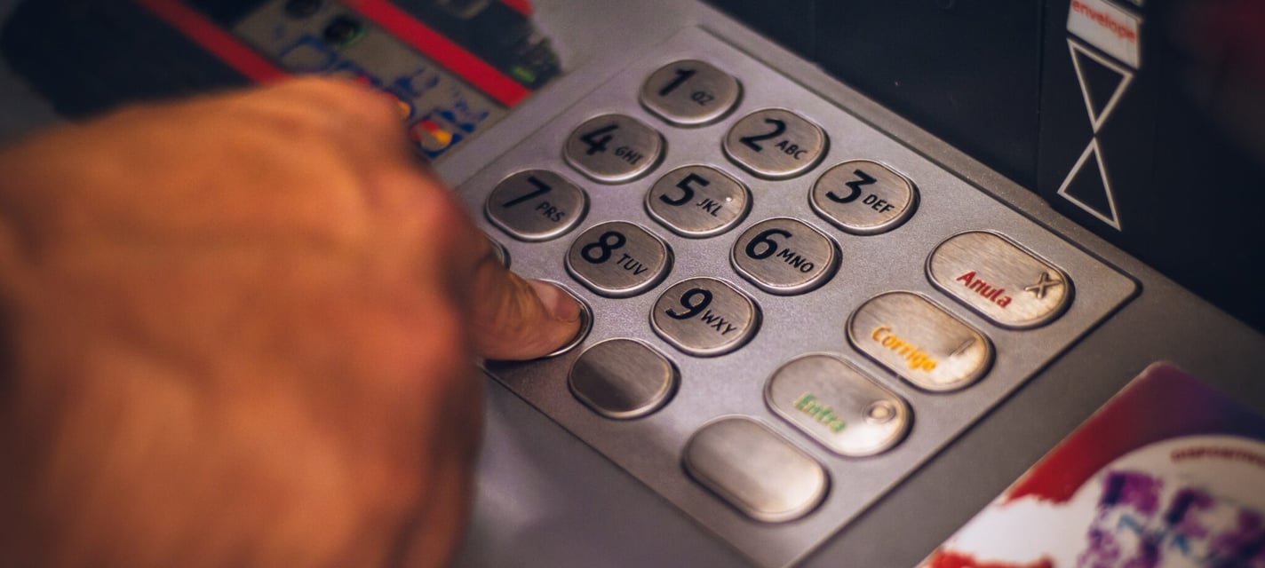 A person entering a PIN at an ATM.