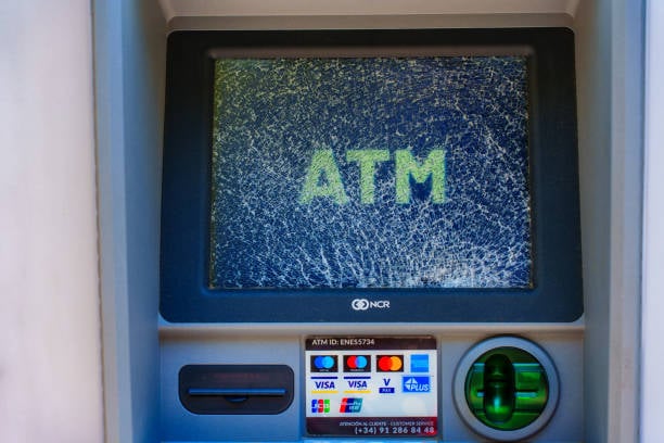 ATM machine with a screen displaying "ATM." Below are card slots and logos of card brands.